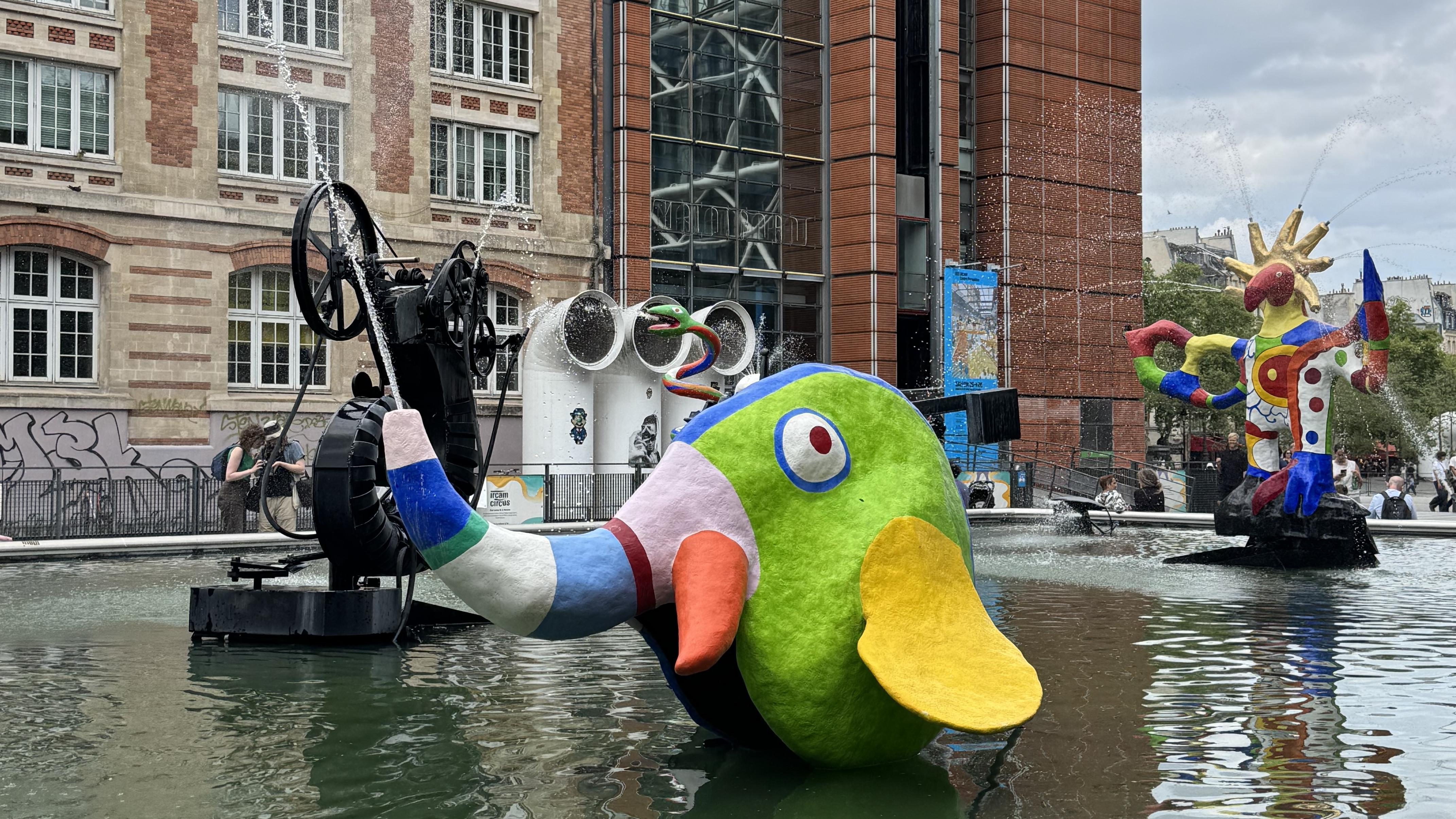 Stravinsky Fountain. A colourful elephant is in the centre of the image. There is water shooting out of the trunk of the elephant