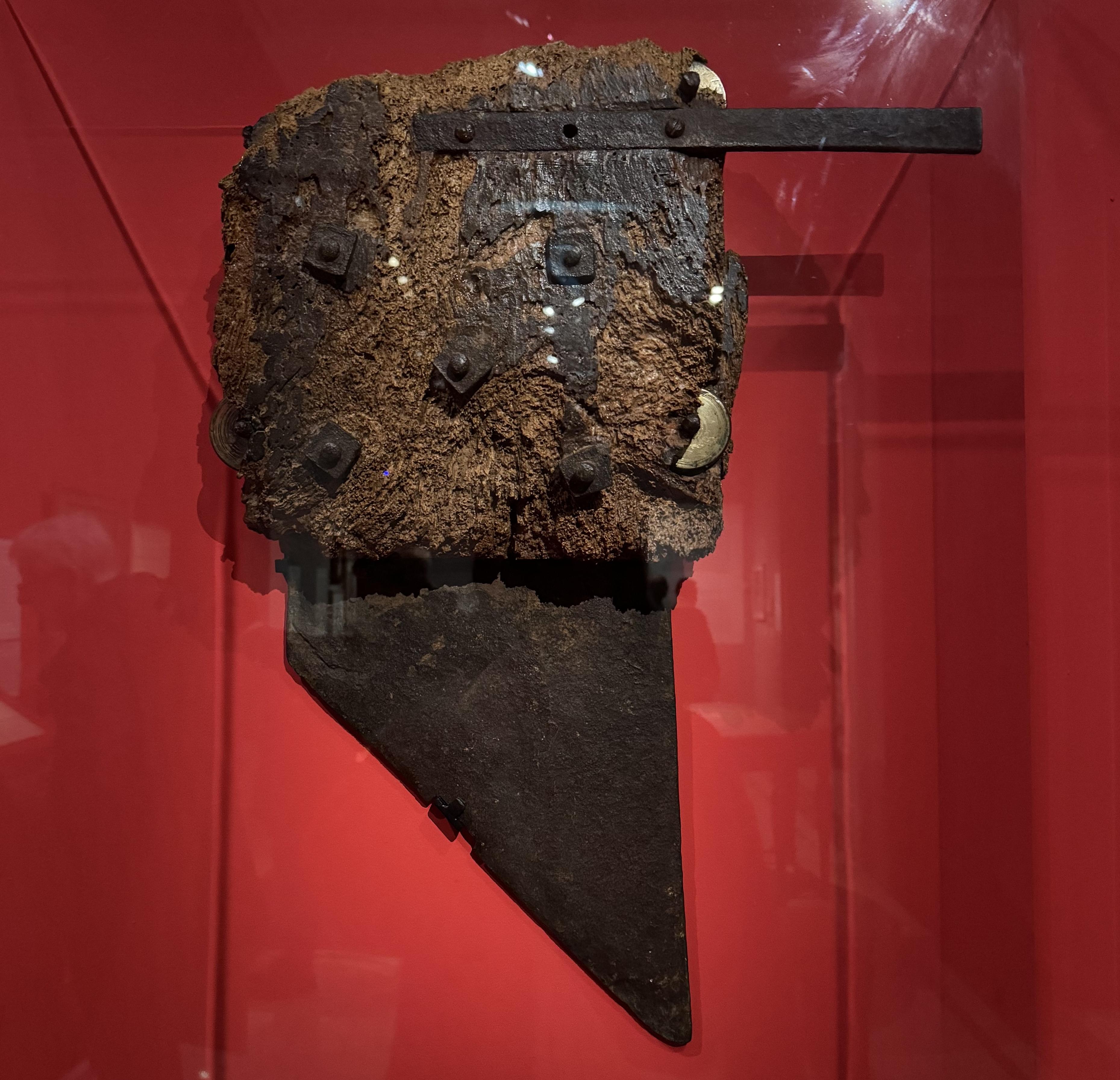 the blade of a guillotine on display. The background of the display case is red