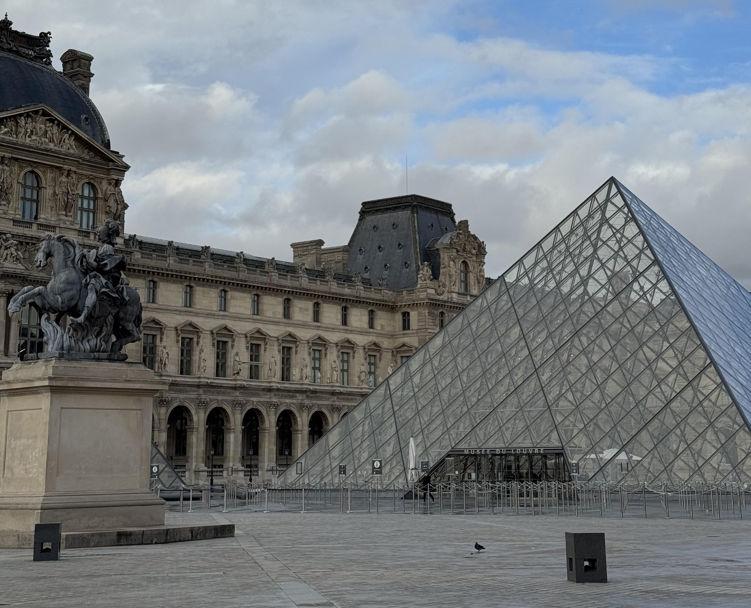 On the left there is a statue of Louis XIV on a horse. To the right there is the glass pyramid to get into the Louvre. Behind you can see one of the wings of the Louvre
