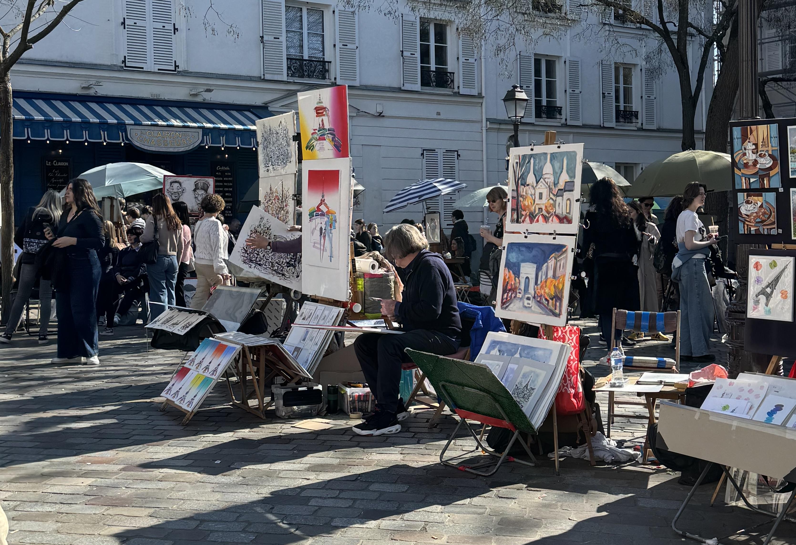 five artist's stands are visible in the photo. They all have paris themed art on display.