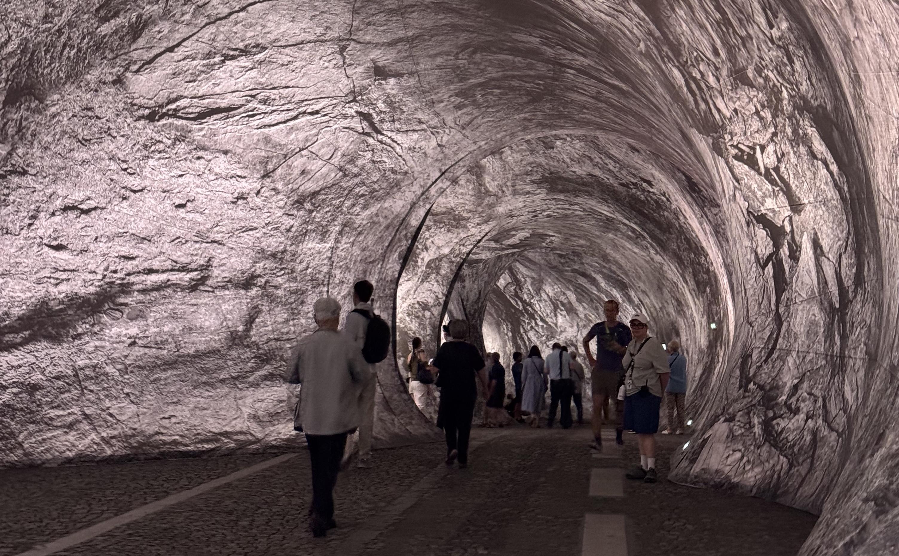 the inside of La Caverne. On the ground you can see the road markings. There are people walking ahead and one member of staff standing on the right. The walls have a purpleish tone to them.