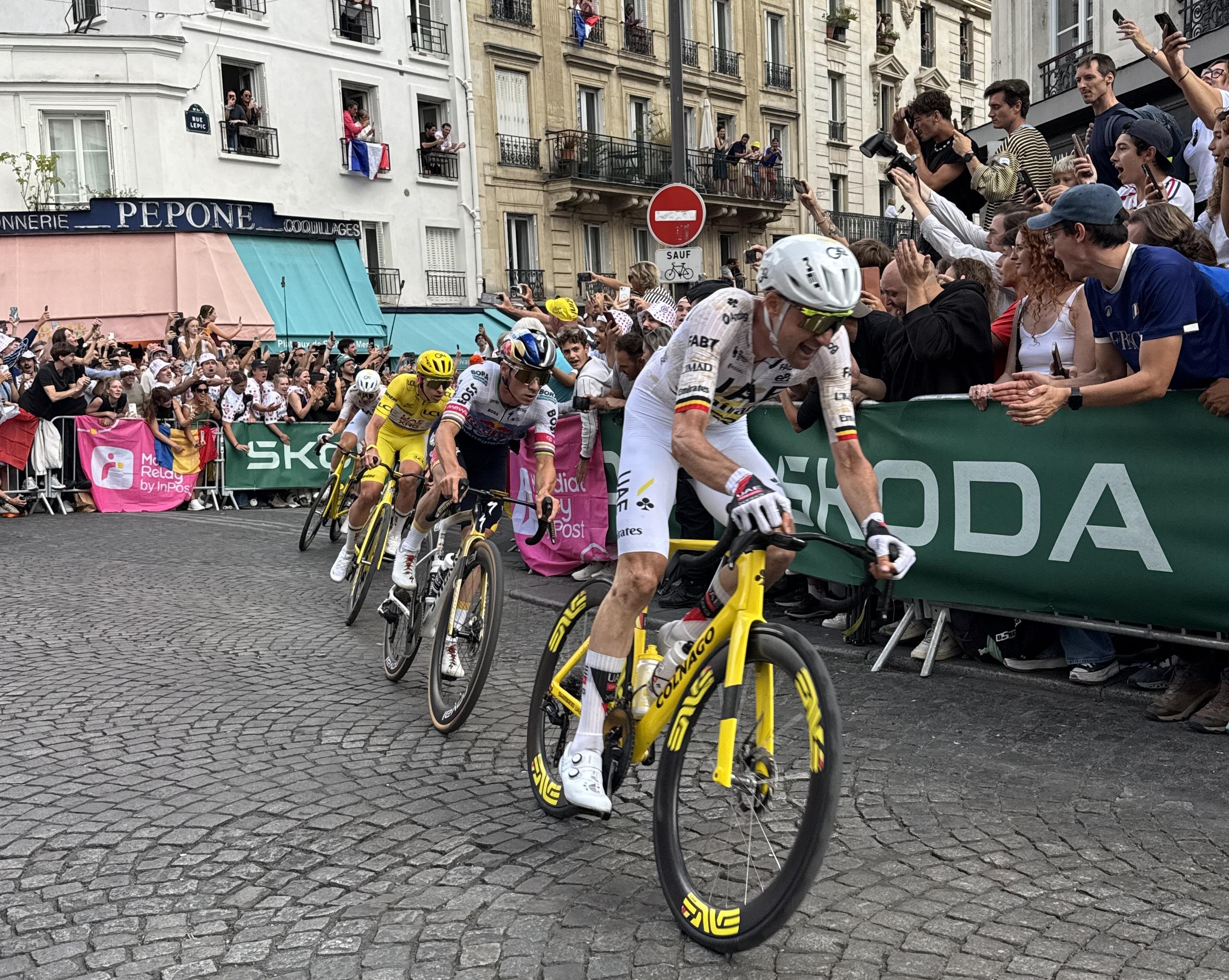 four men cycling. In third position you see the cyclist wearing the Yellow jersey. Position one looks like he is screaming, position two and three have a more neutral focused expression