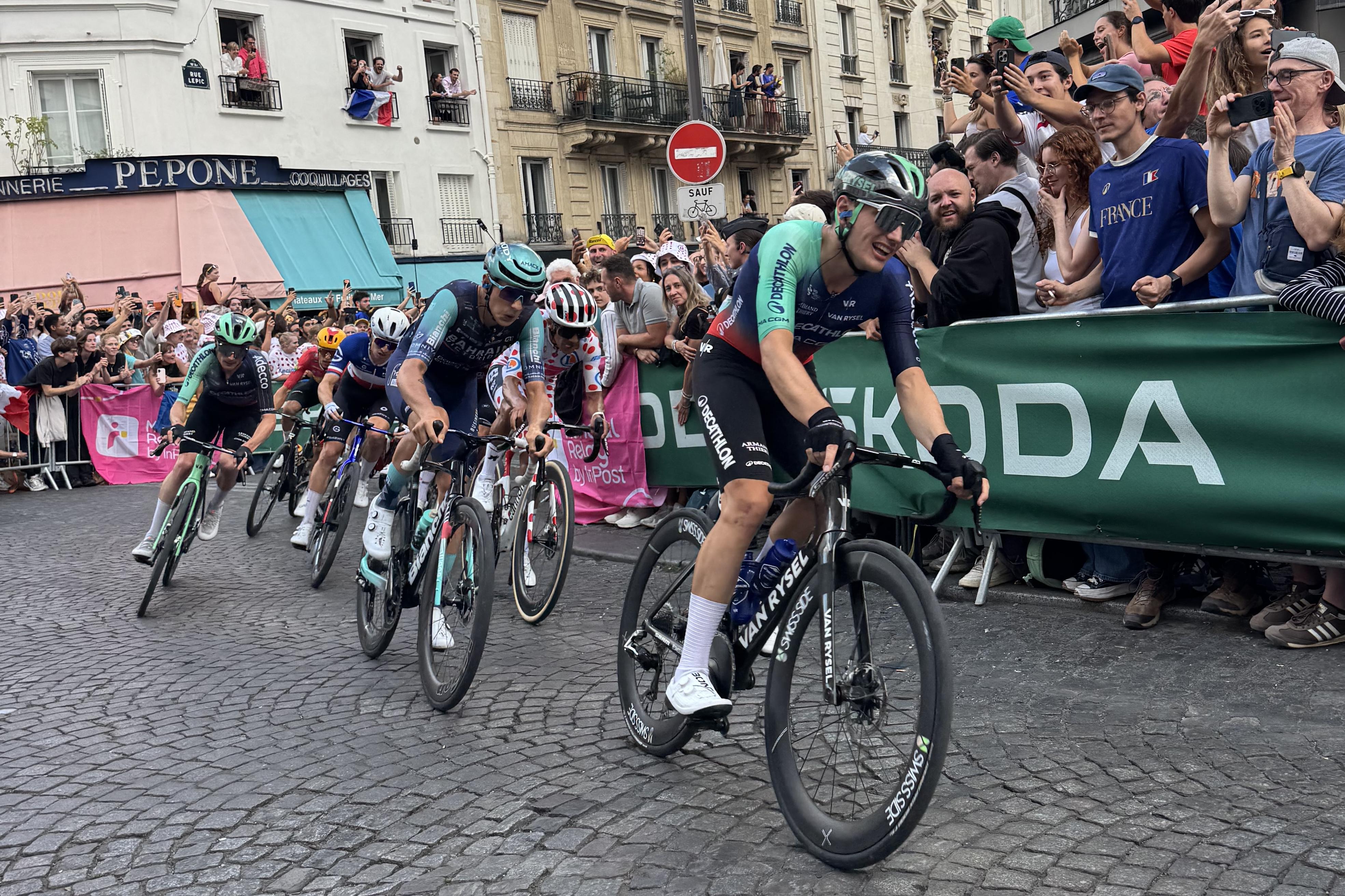 six men cycling. You can tell they're putting on effort by the look on their face. In the front, you have someone riding for the team Decathalon. Third position is the rider in the polka dot jersey