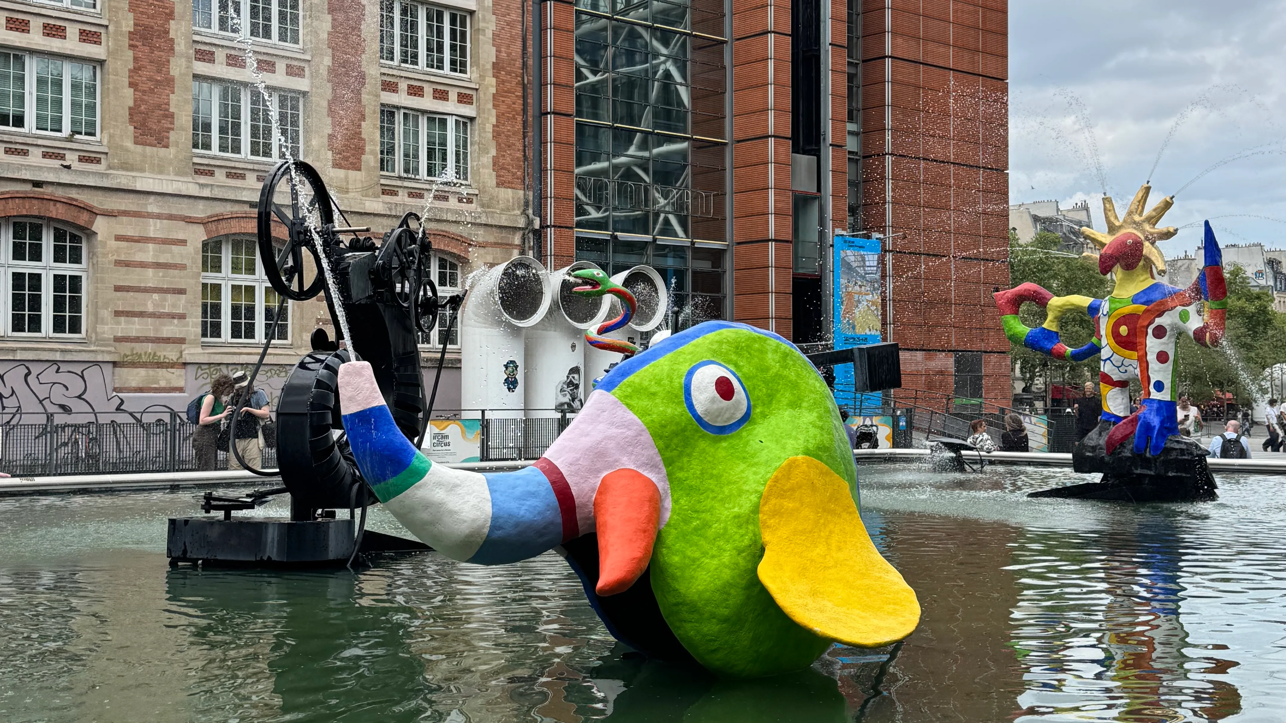 Stravinsky Fountain. A colourful elephant is in the centre of the image. There is water shooting out of the trunk of the elephant