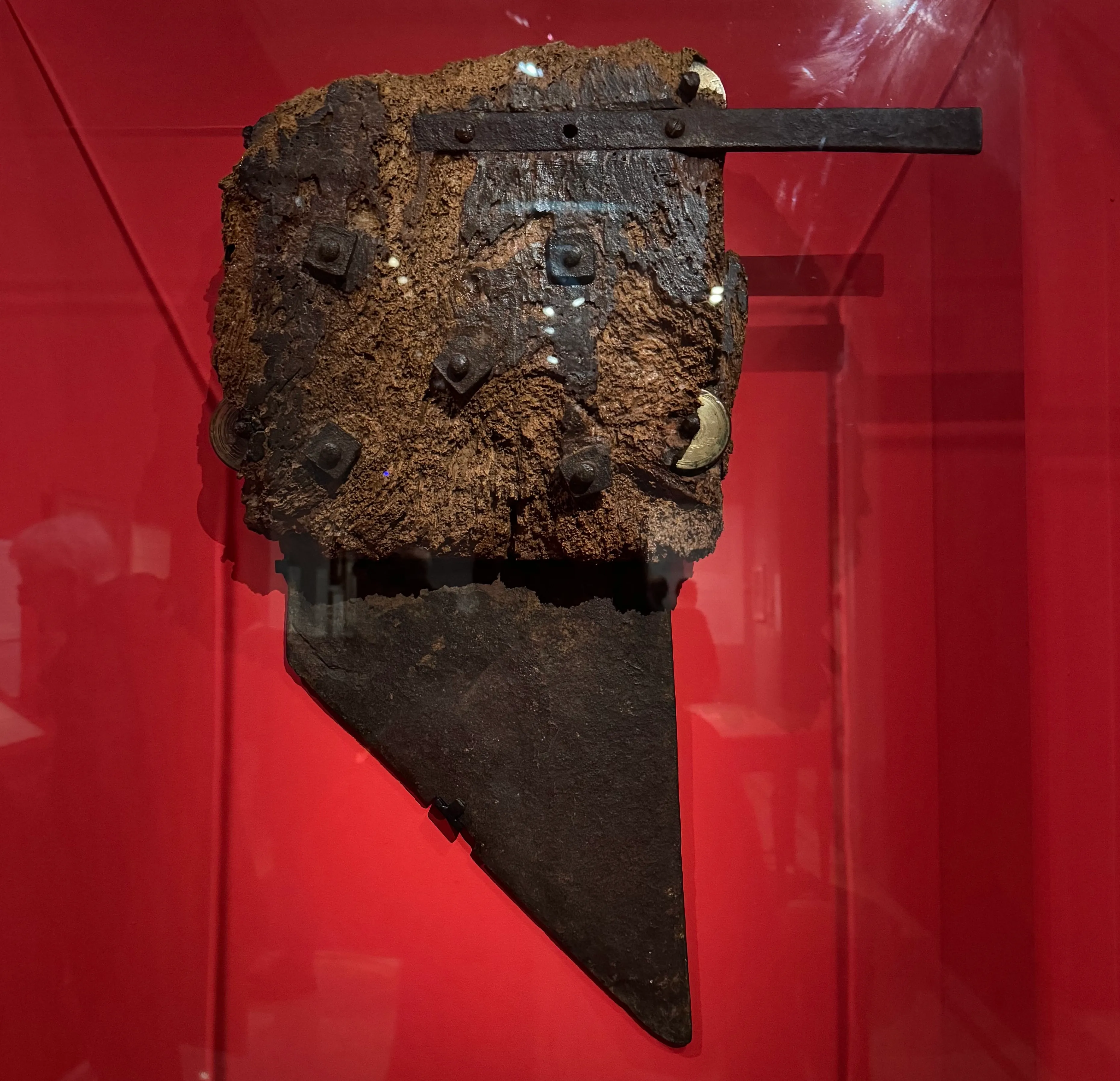 the blade of a guillotine on display. The background of the display case is red