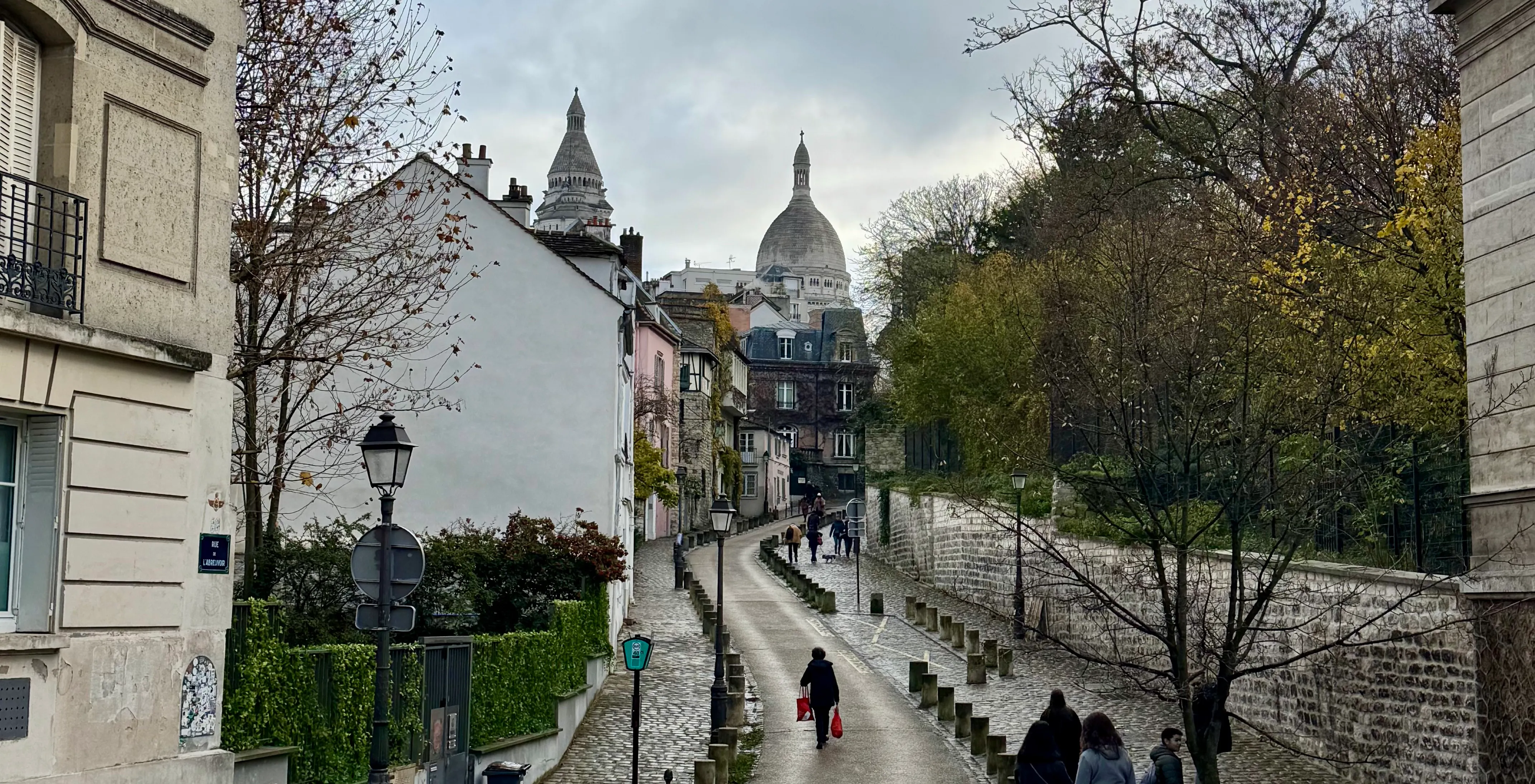 a small street going up a hill with a view of the sacre cœur in the background