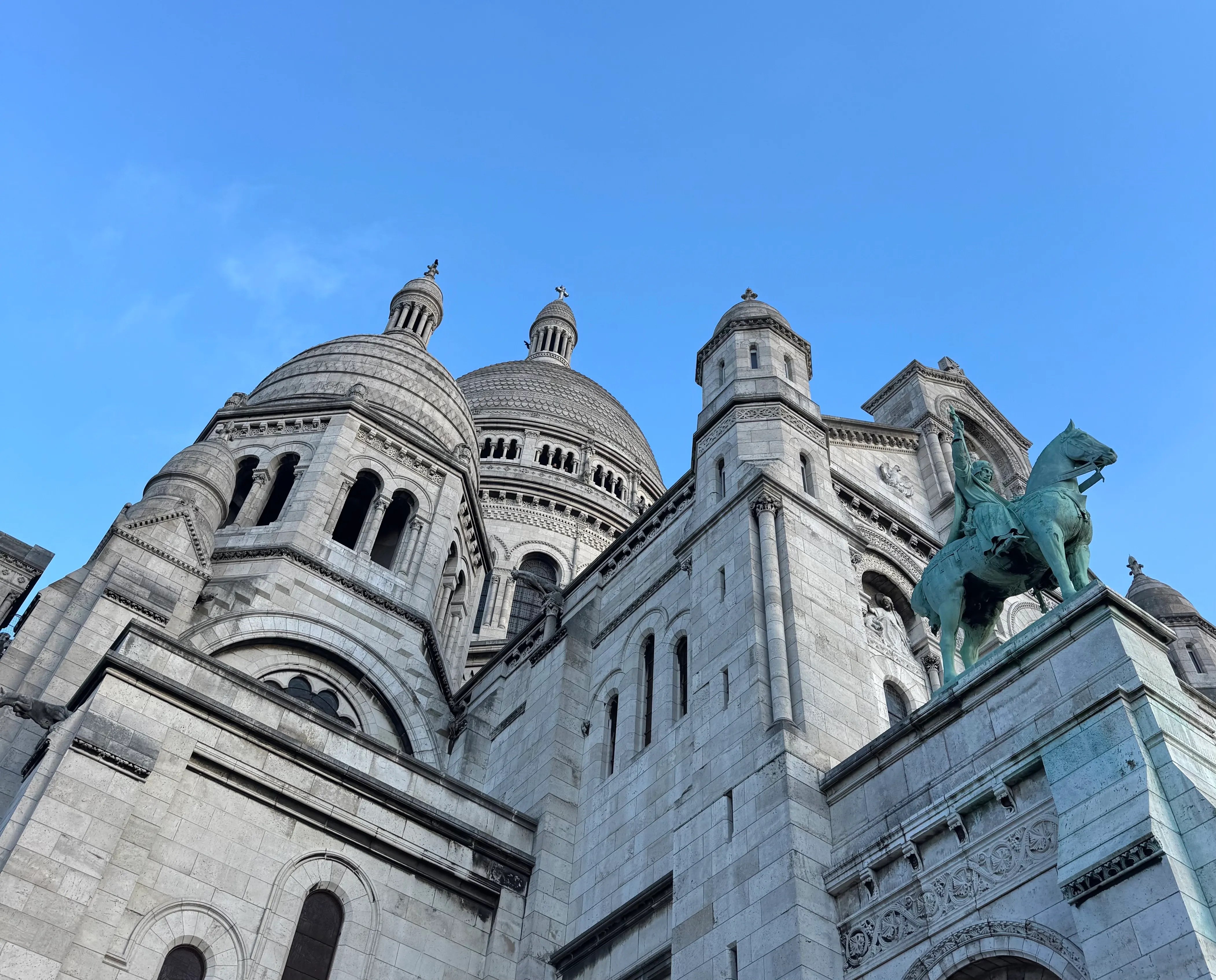 the sacre coeur dome is in the centre. At the right side there is a statue of Louis IX on a horse