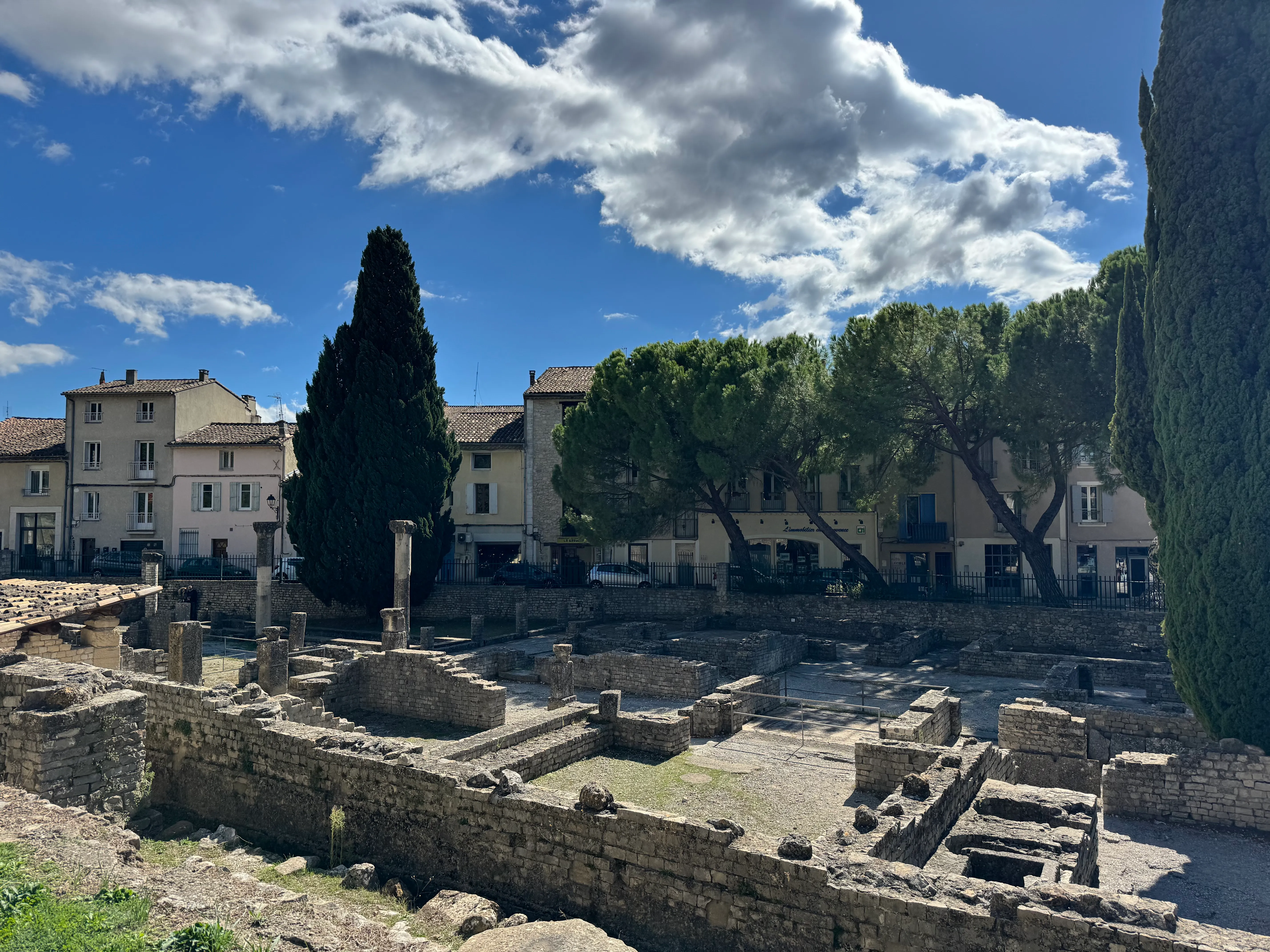 the archaeological site with cars and modern day houses just outside